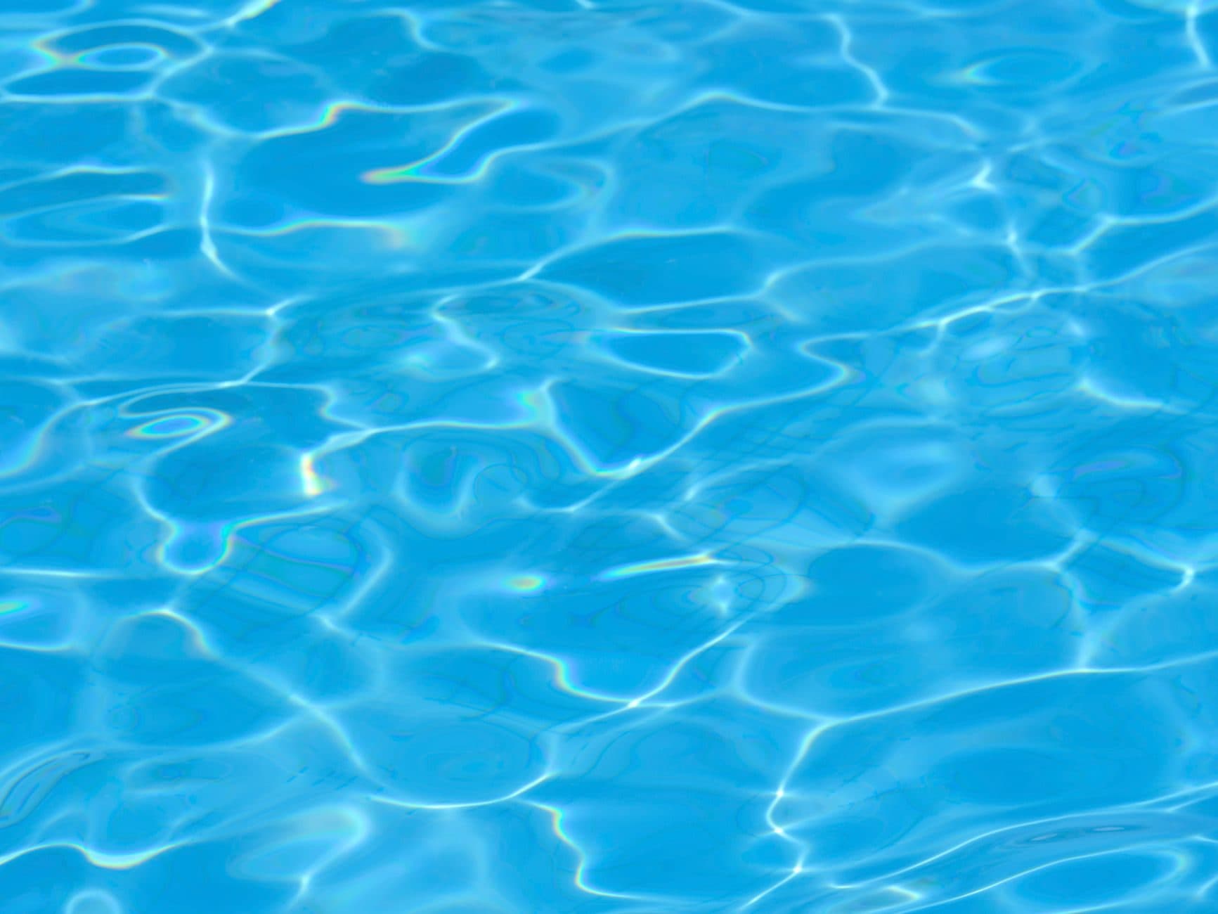Clear blue swimming pool water rippling in sunlight