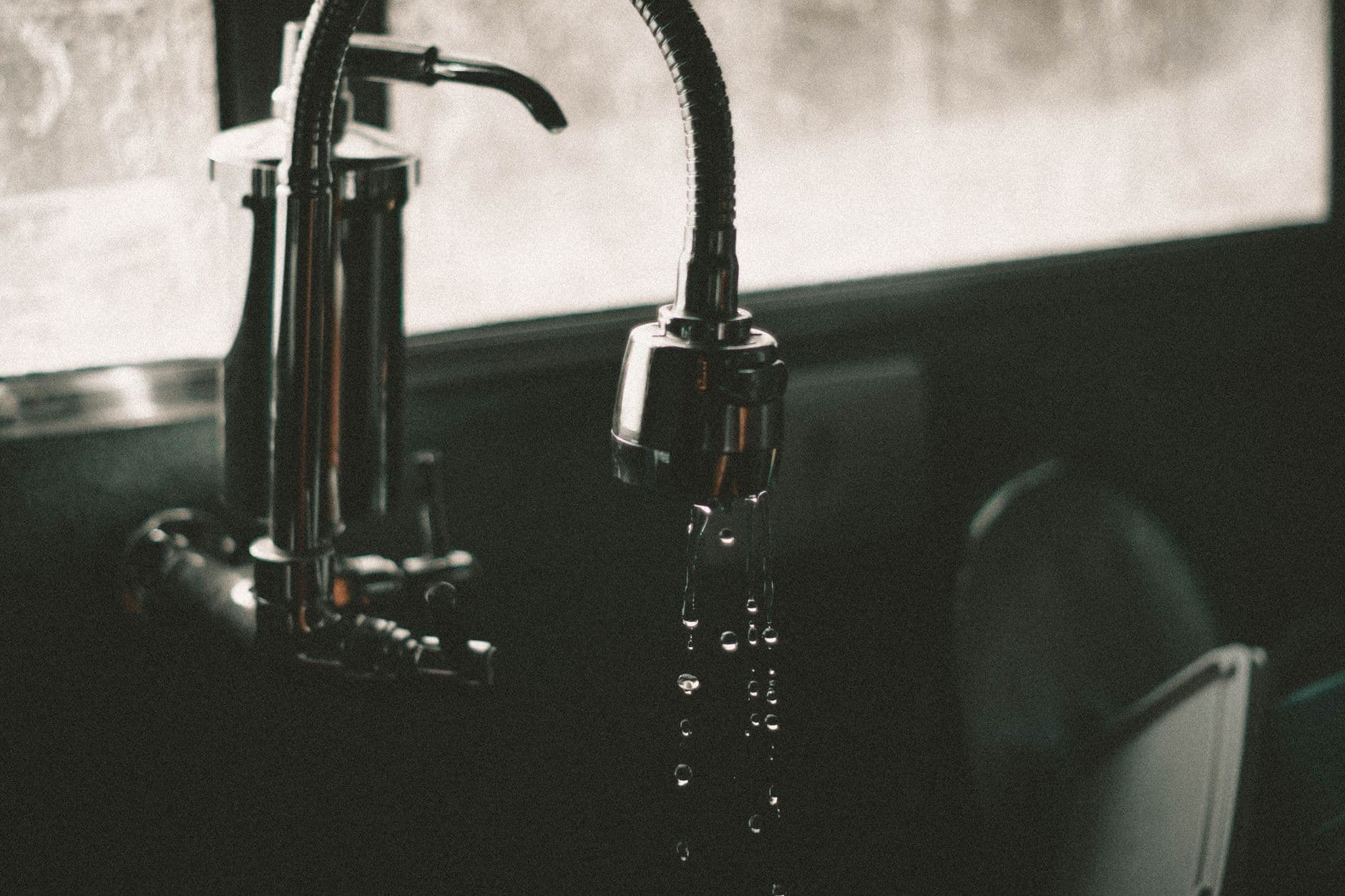 Close-up of a kitchen faucet with water droplets falling into the sink